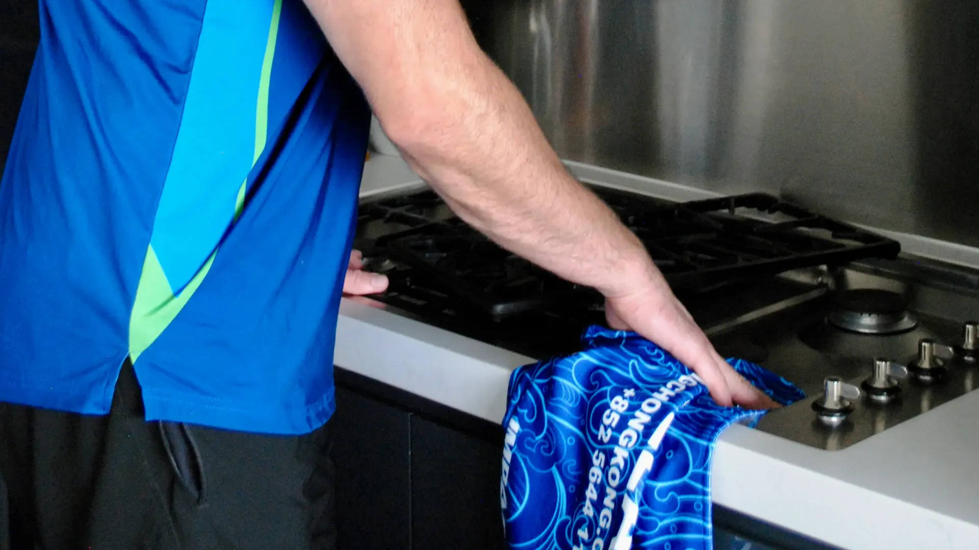 Green Clean cleaner cleaning a gas hob with a branded cloth during a tenancy clean